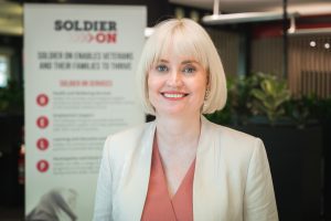 Female CEO standing in front of Soldier On banner