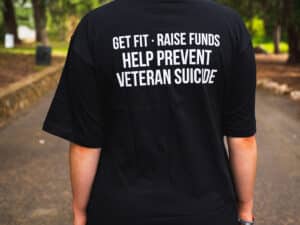 Back view of a woman in a black March On tee shirt with writing that says get fit, raise funds, help prevent veteran suicide in white.