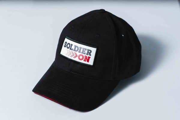Front and side view of a black baseball cap with red sandwich peak, and a white patch with the Soldier On logo in dark grey and red.