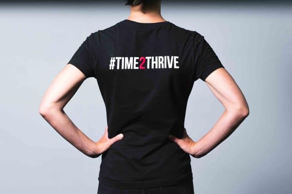 Back of womans black tee shirt with hashtag time two thrive logo in red and white.
